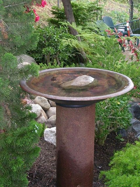 Bird bath made from copper fire pit and steel pipe.