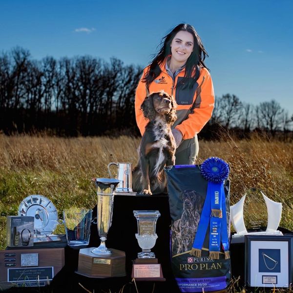 Woman with dog and trophies outdoors.