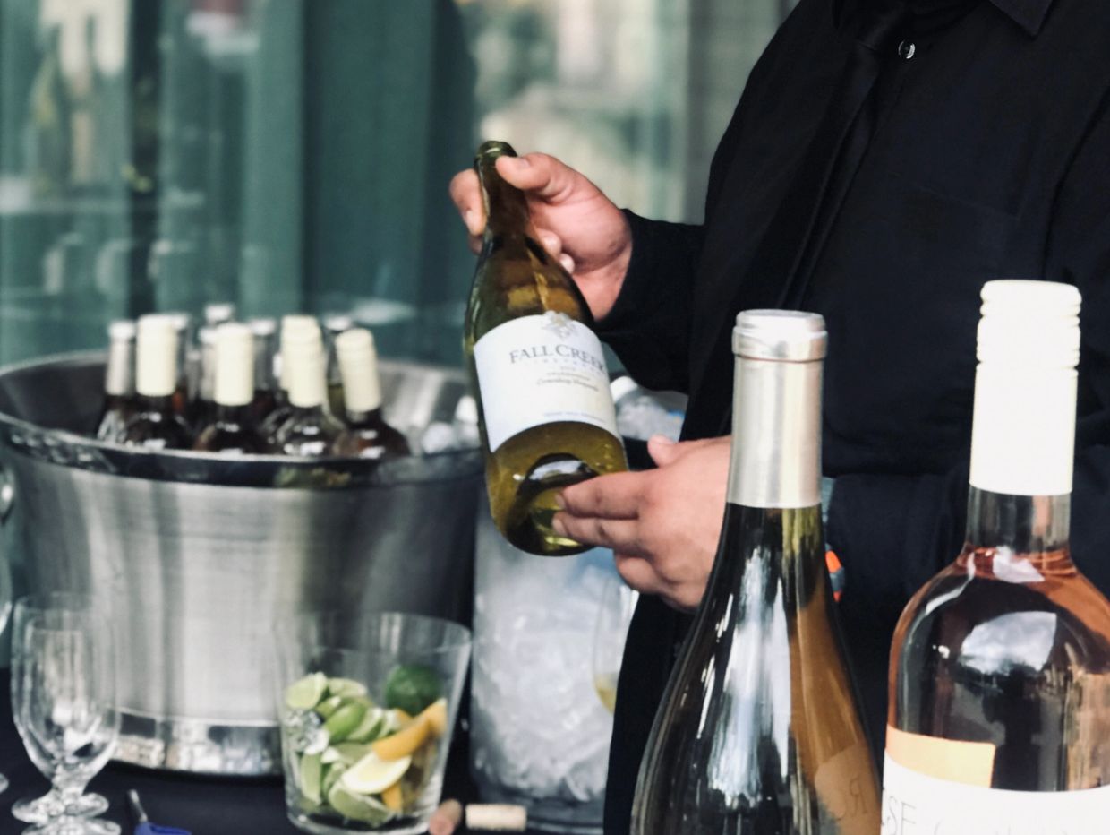 Person holding a bottle of wine labeled Fall Creek.