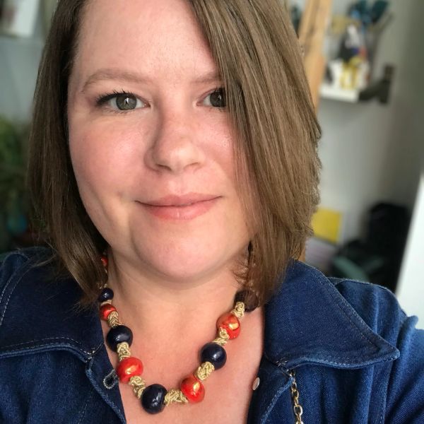 Woman with a blue jacket and beaded necklace.