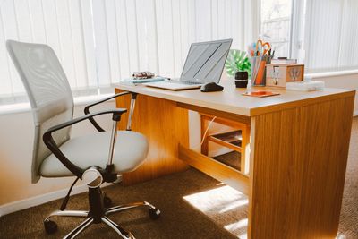 Minimalist wooden desk setup with laptop and office chair.