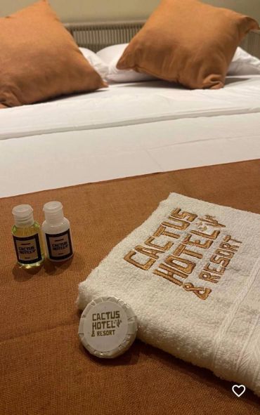 Two small bottles and a towel with 'Cactus Hotel & Resort' embroidery.