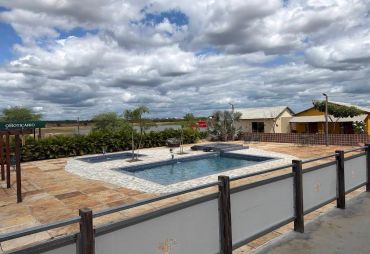 Outdoor swimming pool with cloudy sky and countryside backdrop.