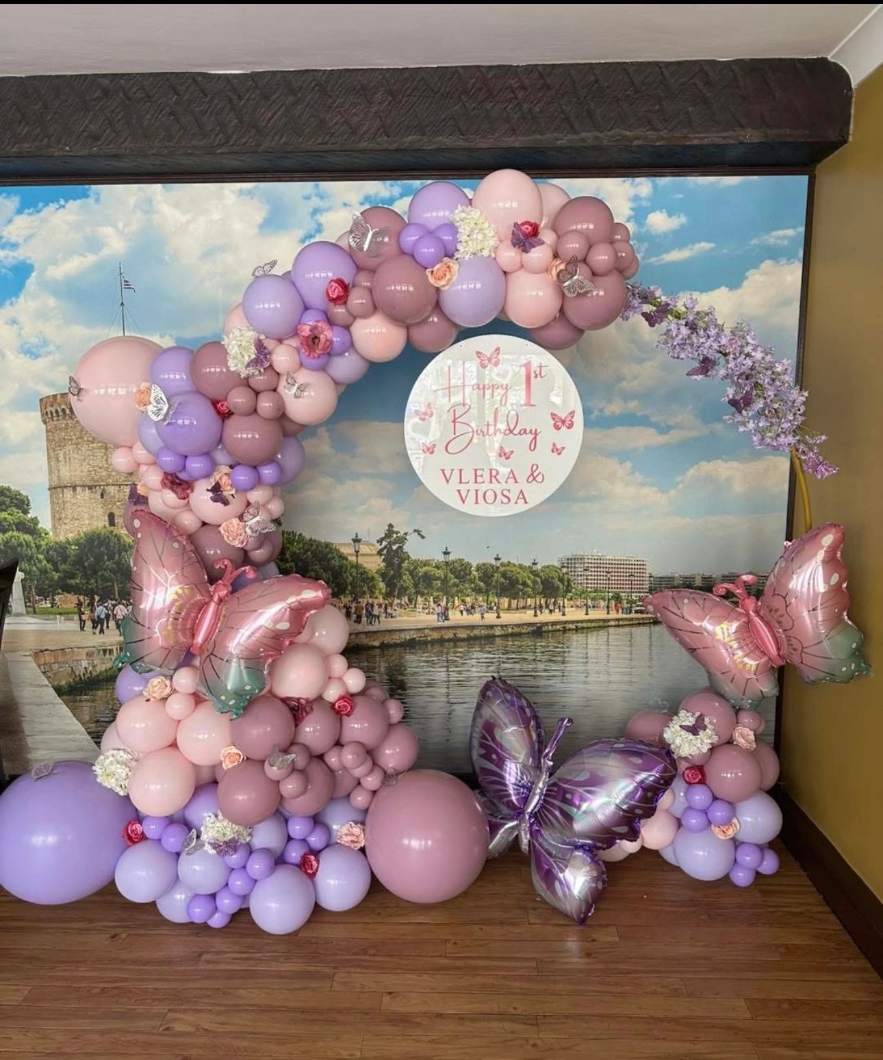 Colorful balloon arch with butterflies for a first birthday celebration.