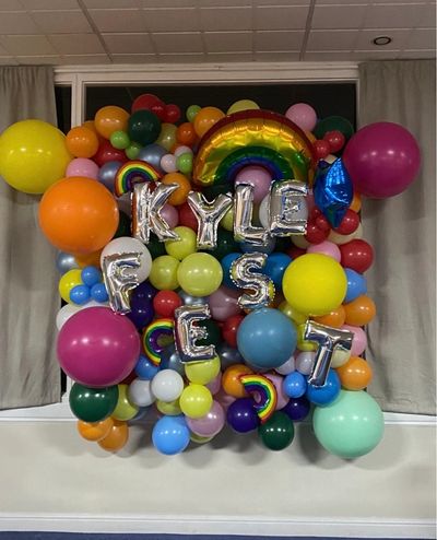 Colorful balloon arrangement with silver letter balloons spelling "KYLE FSCET".
