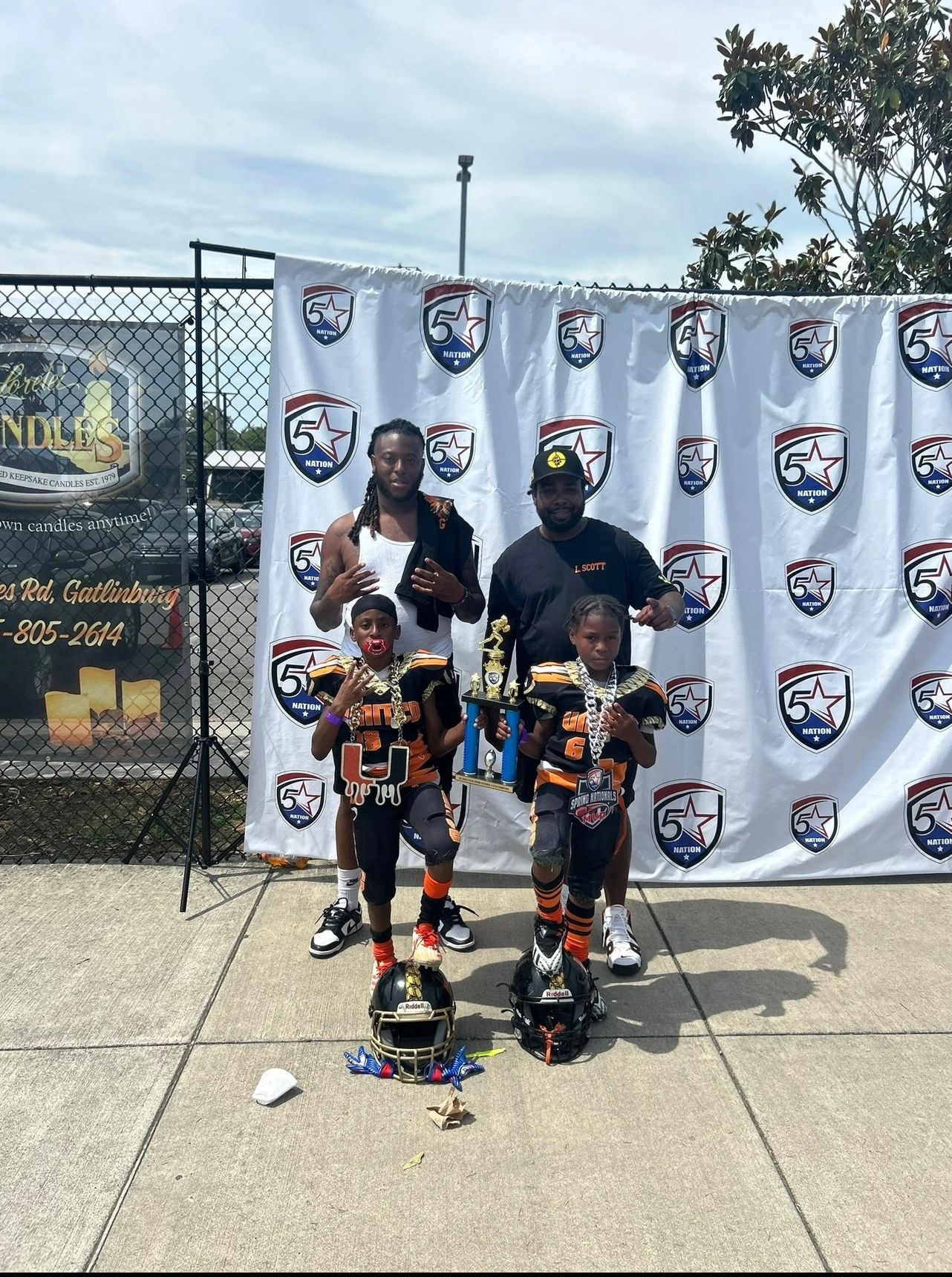 Two young football players with coaches holding a trophy at a 5 Star Nation event.