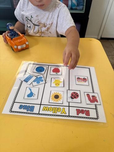 Child sorting color-coded cards into blue, yellow, and red categories at a yellow table.