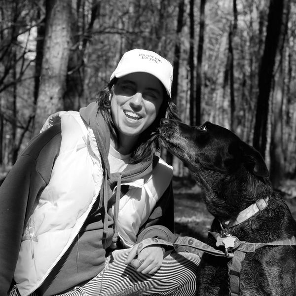 Professional dog handler smiles as dog attempts a kiss after successful loose leash walk