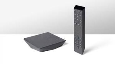A sleek black media streaming device with a matching remote control.