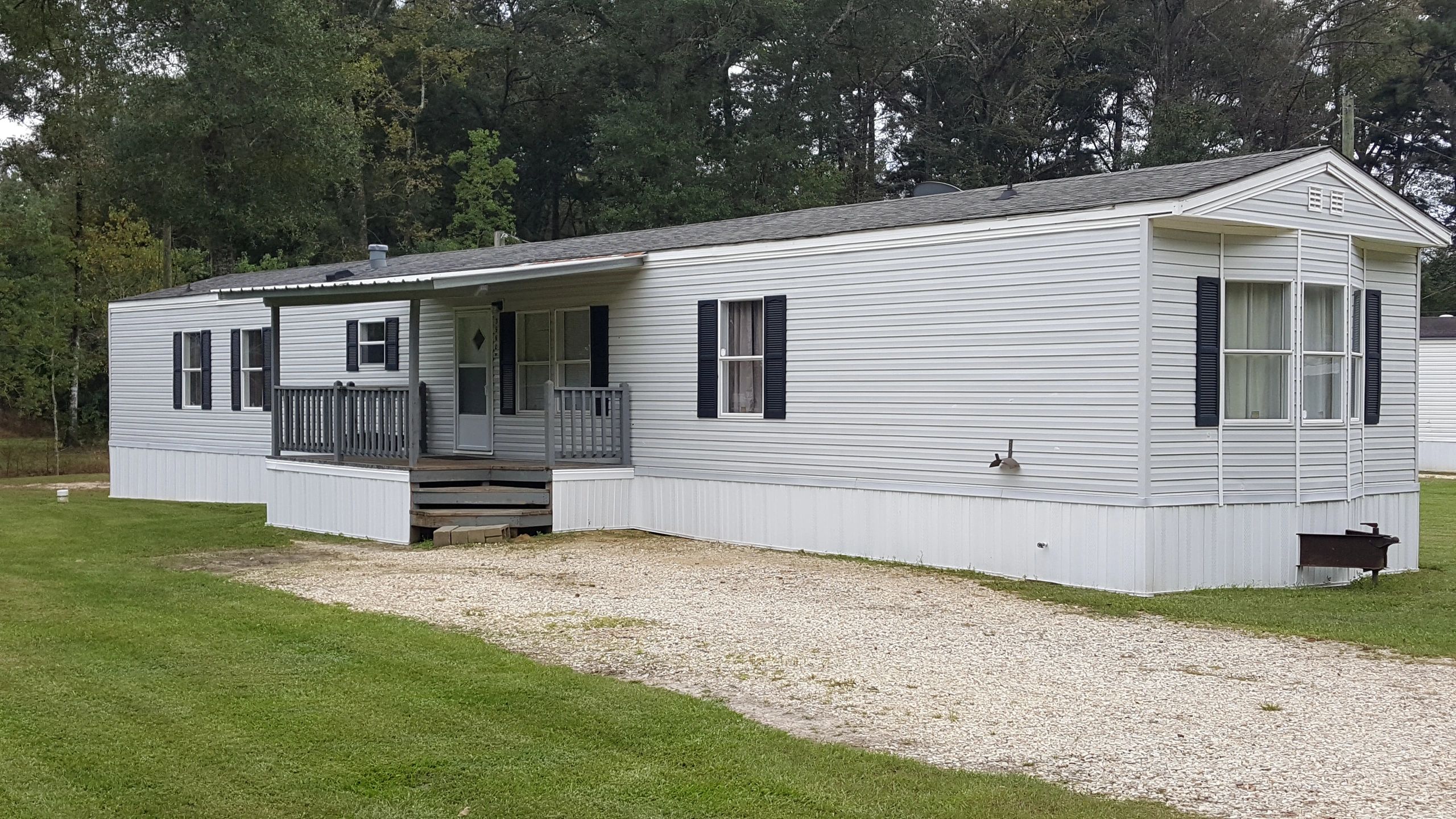 White mobile home with a small porch and green lawn.