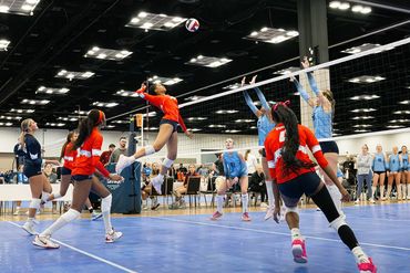 Indoor volleyball match with players in action preparing to hit the ball.