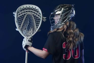 Female lacrosse player holding a goalie stick wearing helmet and jersey number 30.