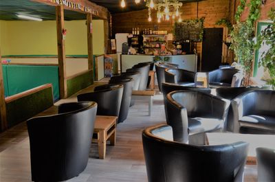 Seating area with tub chairs & small tables. Coffee shop located at the end.