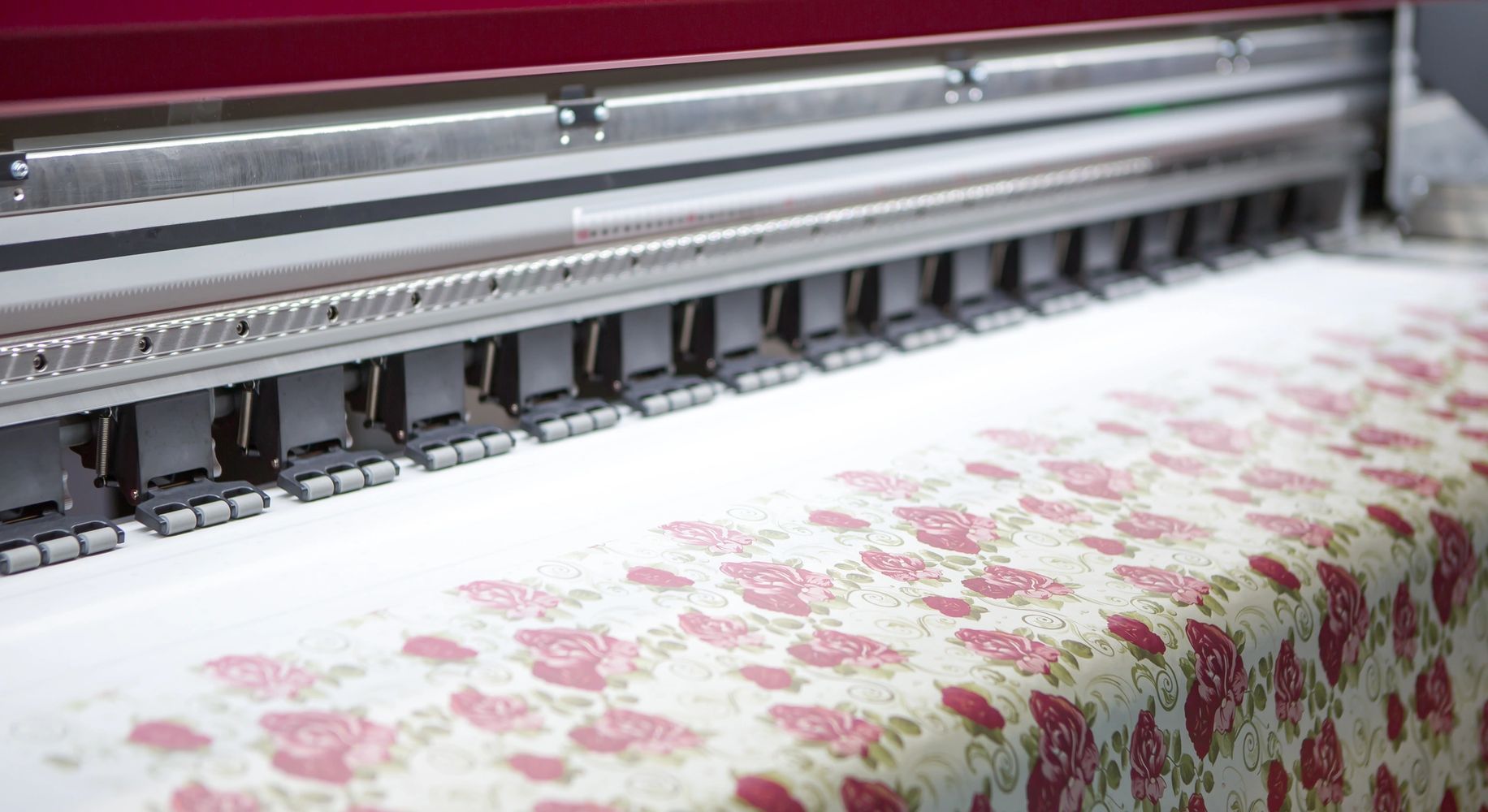A large printer printing floral patterns on fabric.