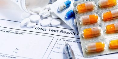 Drug test results form with pills and capsules on a table.