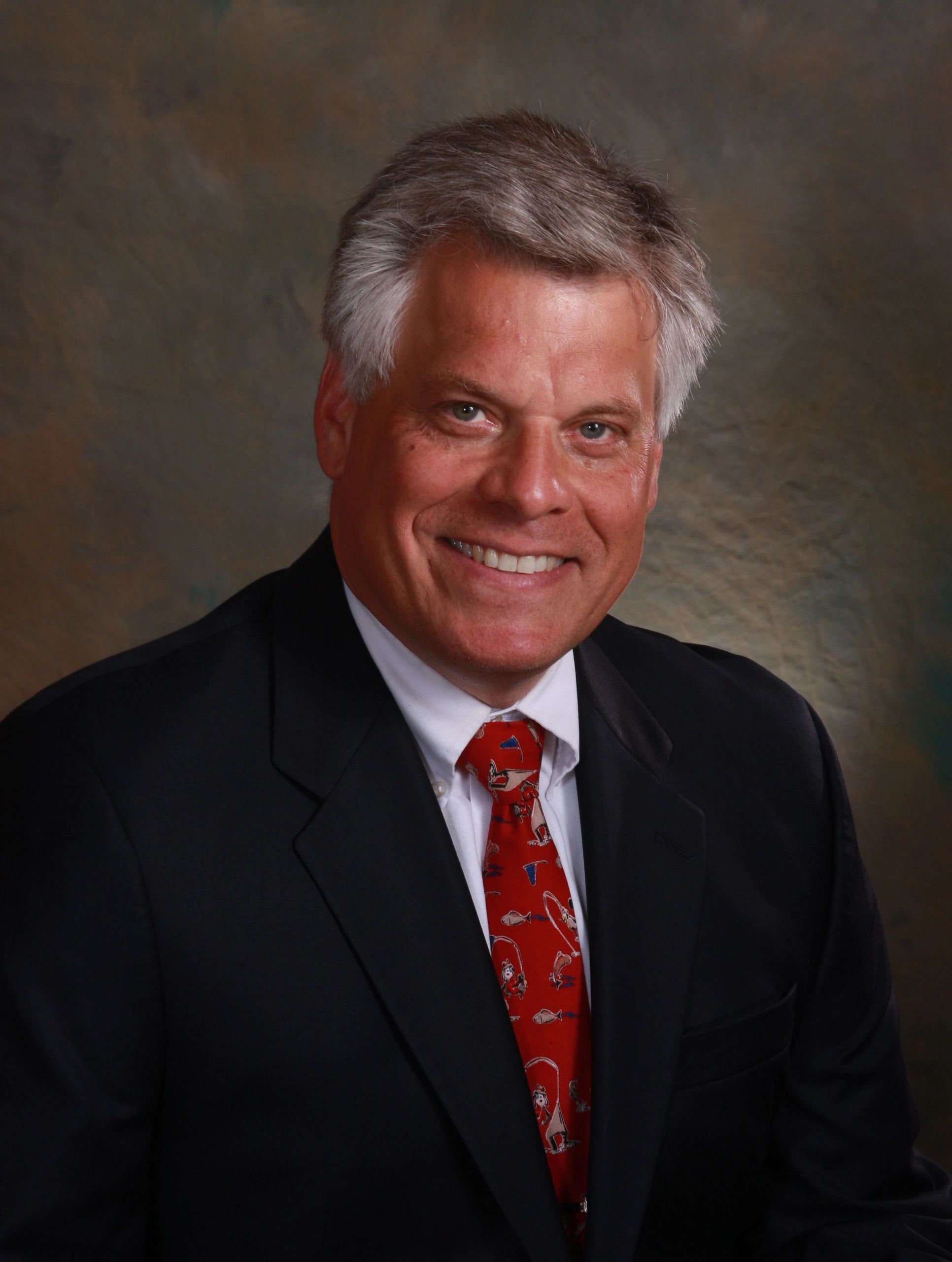 Smiling man in a suit with a red tie.