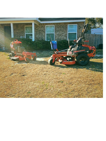 Two red zero-turn lawn mowers on a dry lawn in front of a brick house.