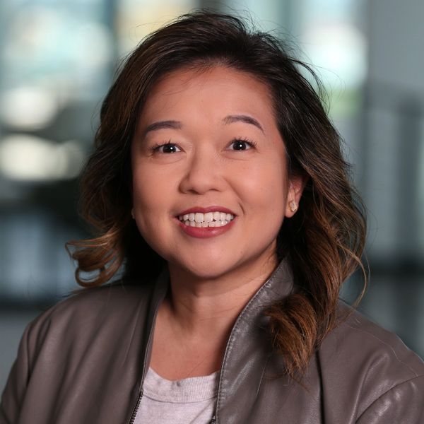 Smiling woman with wavy hair in a leather jacket.