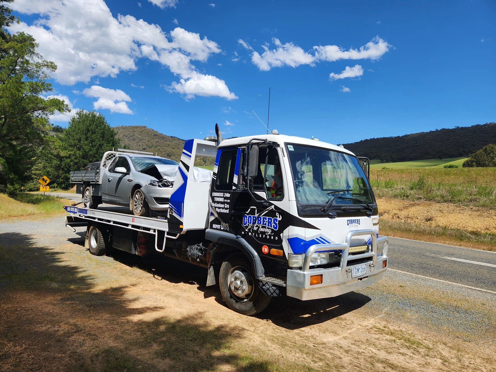 A tow truck with a damaged vehicle stopped on Myrtleford-Yackandandah Rd