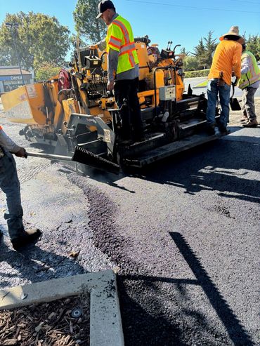 Integrous Paving crew operating paving equipment while installing fresh asphalt on a roadway.