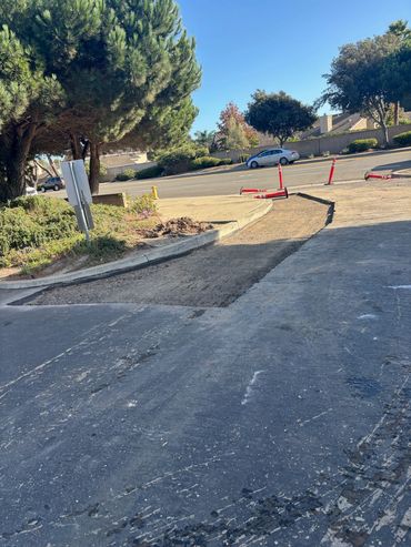 Integrous Paving completed asphalt repairs along a residential street near the curb and sidewalk.