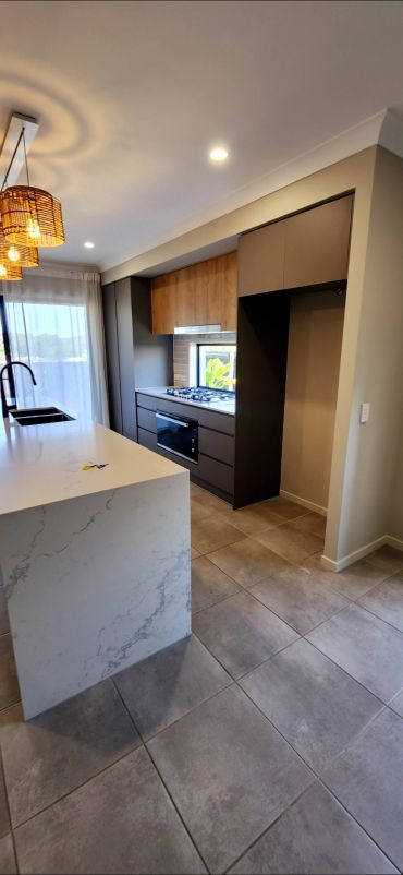 Modern kitchen with marble island and dark cabinetry.