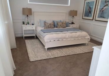 Cozy bedroom with white furniture and soft lighting.