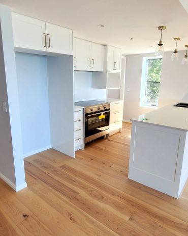 Modern kitchen with white cabinets and wooden floor.