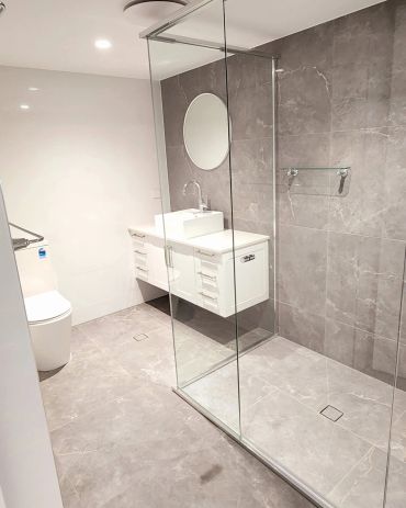 Clean modern bathroom with glass shower and white vanity.
