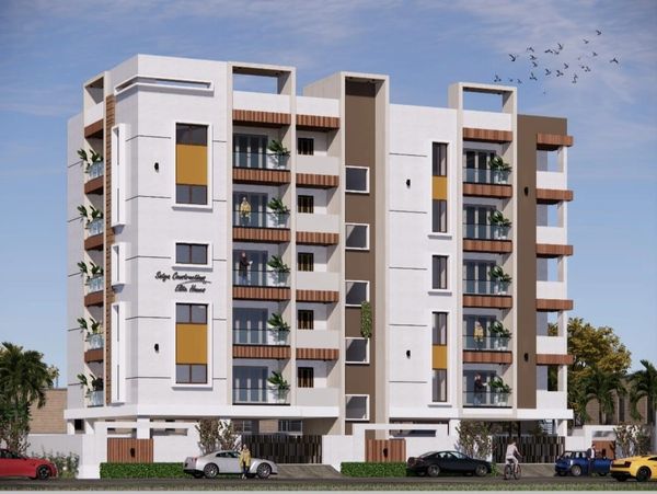 Modern multi-story residential building with balconies and greenery under a clear sky.