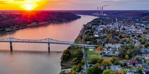 Sunset over a river with a bridge and town on the right side.