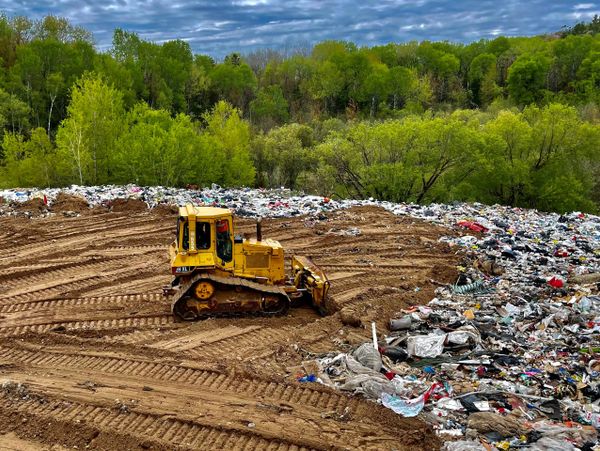 An overhead view of a landfill with a landfill compactor moving the trash to the side.