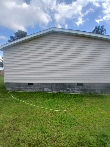 Clean side of a house with fresh grass and blue sky.