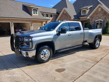 Silver heavy-duty Chevrolet 3500 HD truck parked in front of a house.