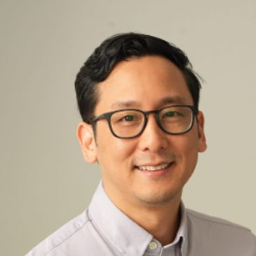 Smiling man wearing glasses and a collared shirt.