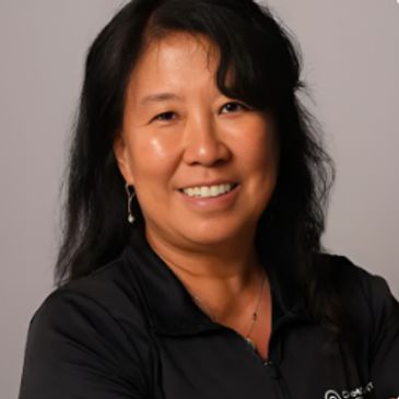 Smiling woman with black hair in black top.