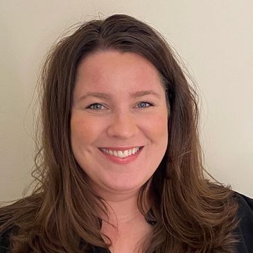 Smiling woman with brown hair and light background.