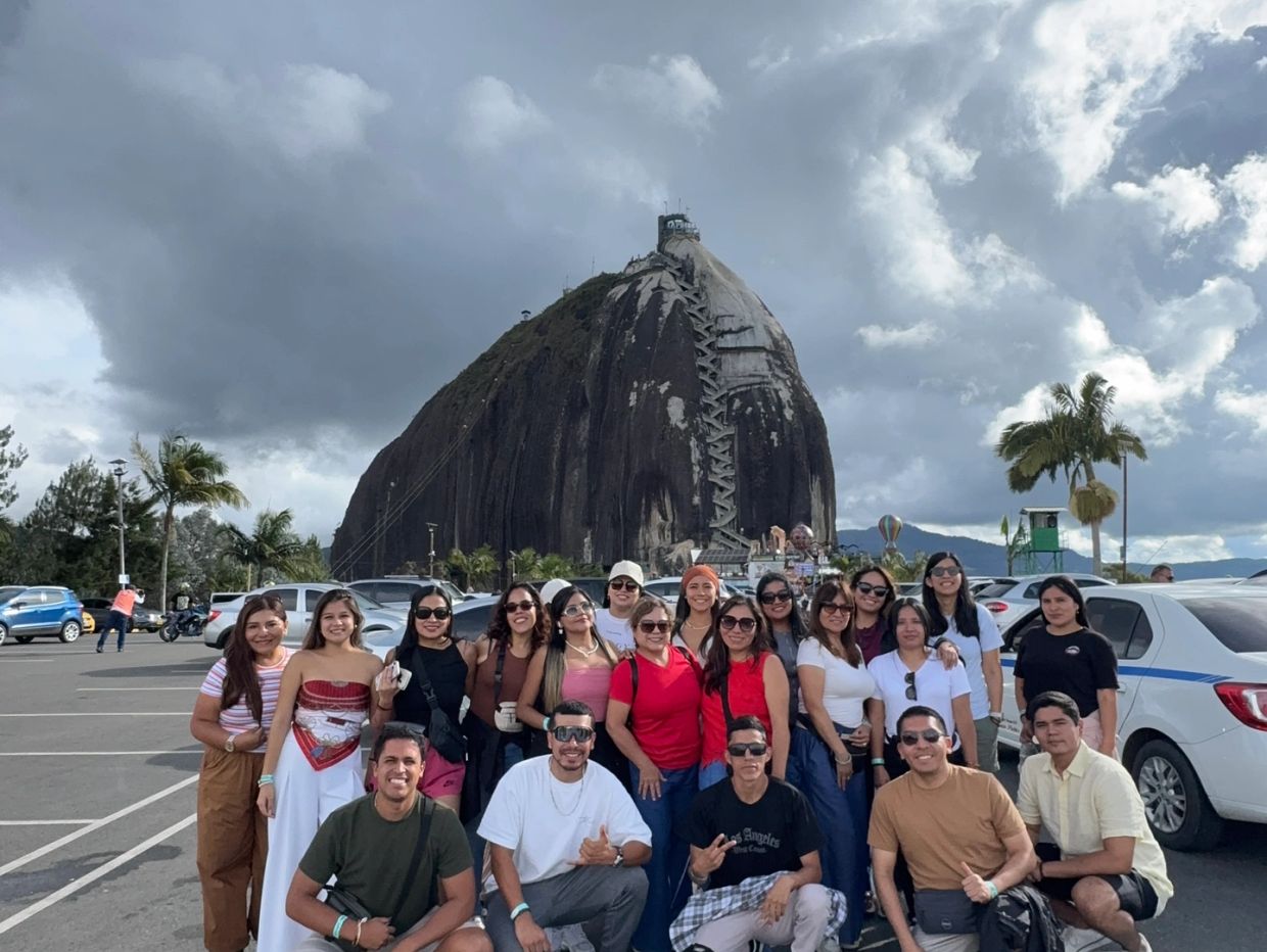 Grupo de personas frente a una gran roca con escaleras.
