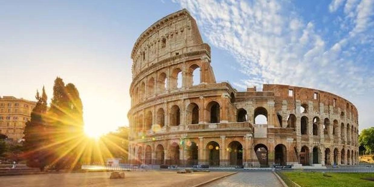 Coliseo Romano al atardecer con el sol brillando.