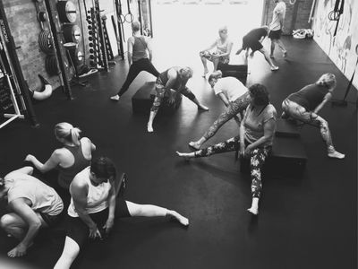Members performing dynamic stretches as part of a warm up to open the hips and get ready for leg wor