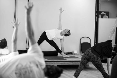Teacher and students performing Utthita Trikonasana (Triangle Pose) in class. Iyengar Yoga shares th