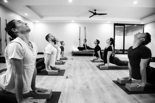 Image inside the yoga studio. Class holding Bhujangasana (Cobra) pose.