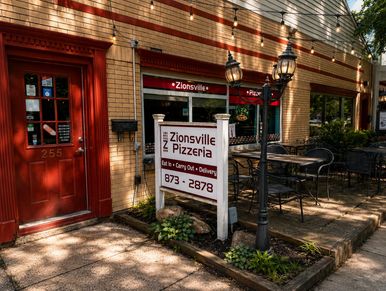 Outdoor view of Zionsville Pizzeria with a sign and seating area.
