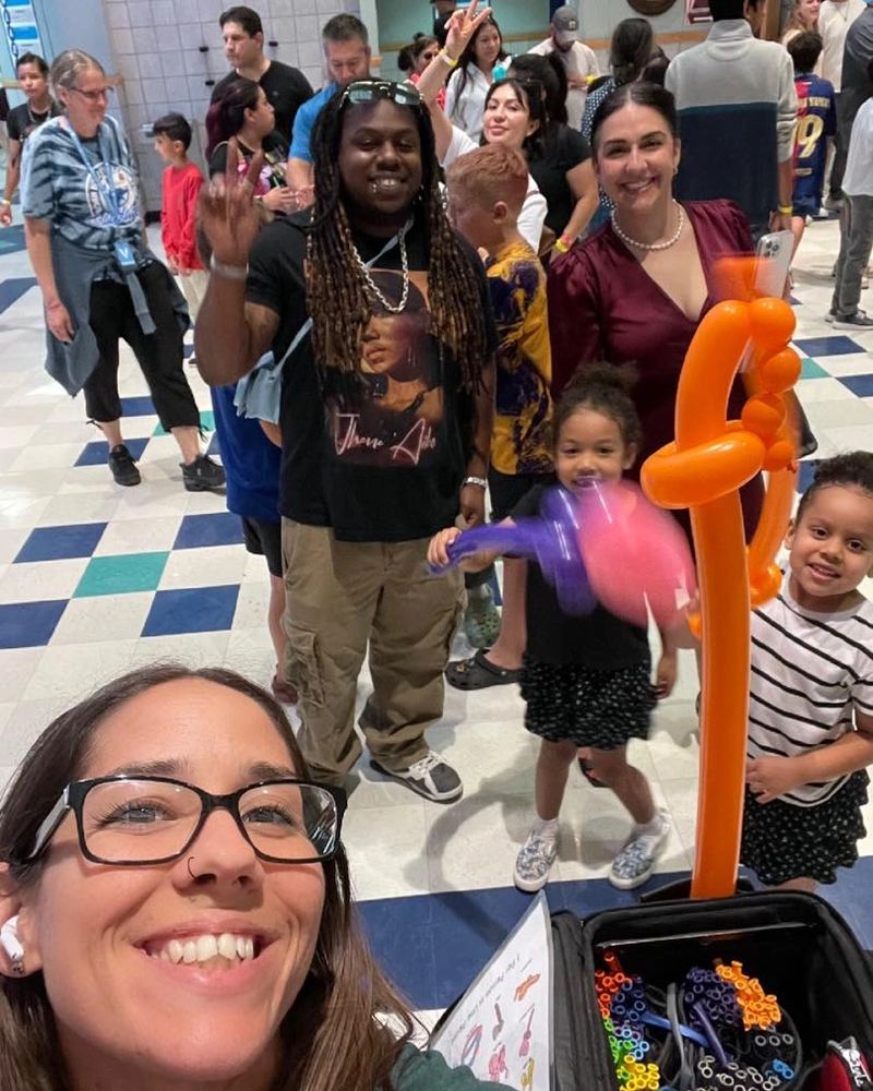 Mandie twisting balloons for happy families at an elementary school carnival.