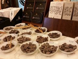 Assorted chocolate samples in bowls labeled with cocoa percentages and flavors.