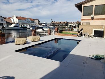 Waterfront pool with dark interior finish and light stone decking