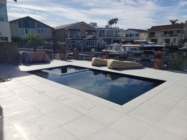 Modern backyard pool area with covered furniture and waterfront view.