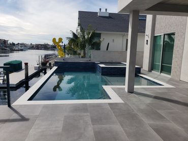 Waterfront pool and raised spa with dark tile and white coping