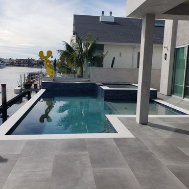 Modern backyard pool with waterfront view and sleek patio tiles.