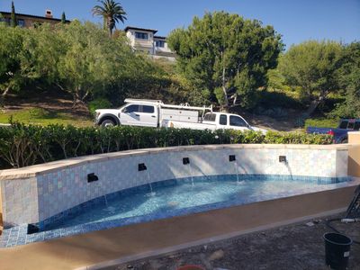 Raised pool wall with new waterline tile and water features under construction